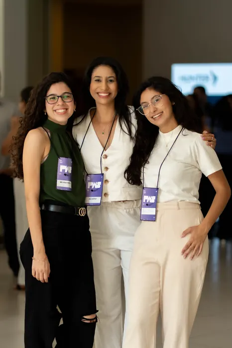 Participantes posam juntas com o crachá do evento