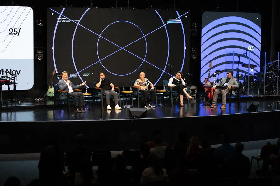 Painel de convidados no palco visto da plateia
